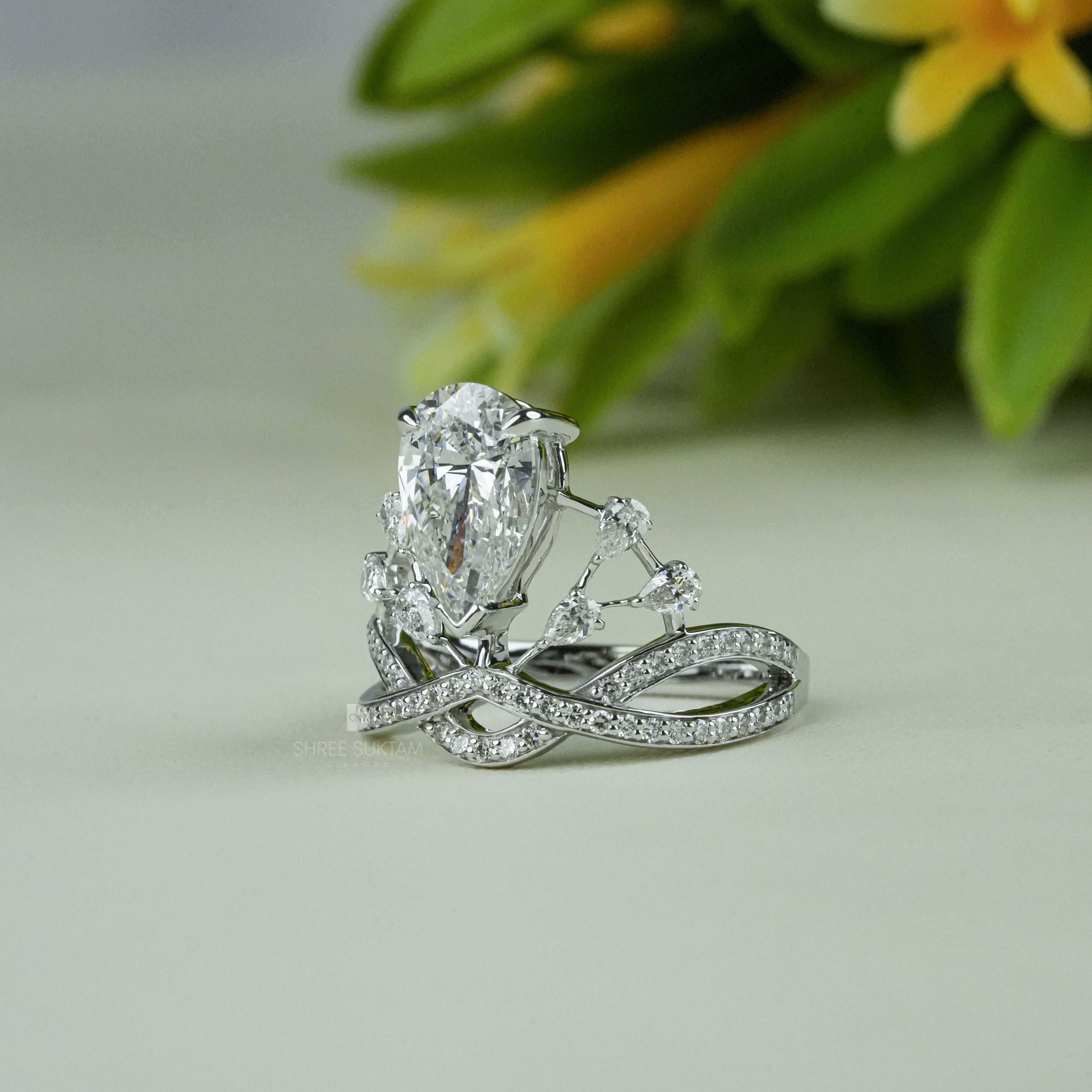 Elegant white gold tiara-inspired engagement ring featuring a stunning pear-shaped center diamond. The crown-style design is accentuated with smaller round diamonds on a double band adorned with pavé-set stones. Perfect for a bride who desires a regal and unique bridal look, this handmade piece combines royalty-inspired elegance with modern sophistication. Ideal as a proposal, promise, or anniversary ring.