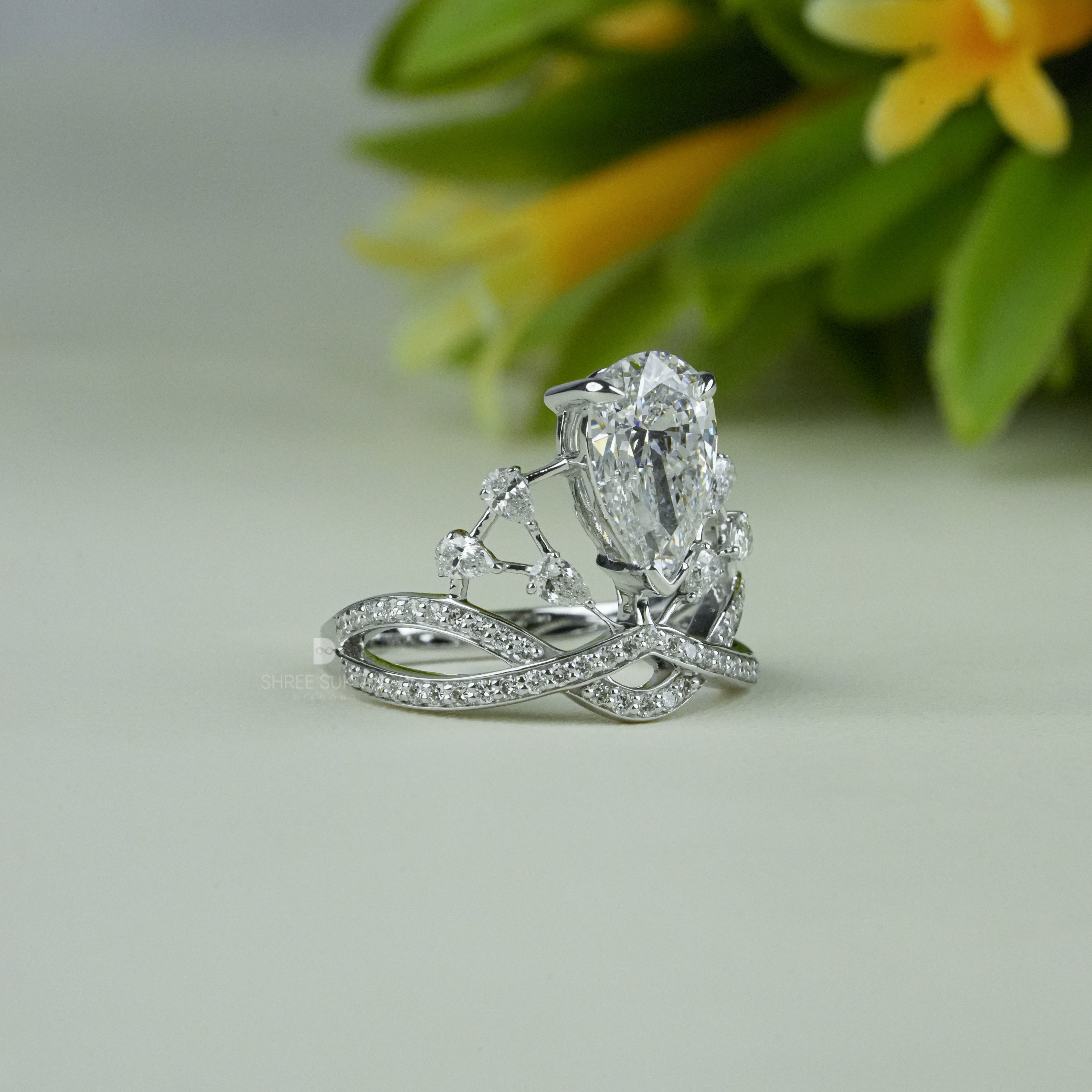 Elegant white gold tiara-inspired engagement ring featuring a stunning pear-shaped center diamond. The crown-style design is accentuated with smaller round diamonds on a double band adorned with pavé-set stones. Perfect for a bride who desires a regal and unique bridal look, this handmade piece combines royalty-inspired elegance with modern sophistication. Ideal as a proposal, promise, or anniversary ring.