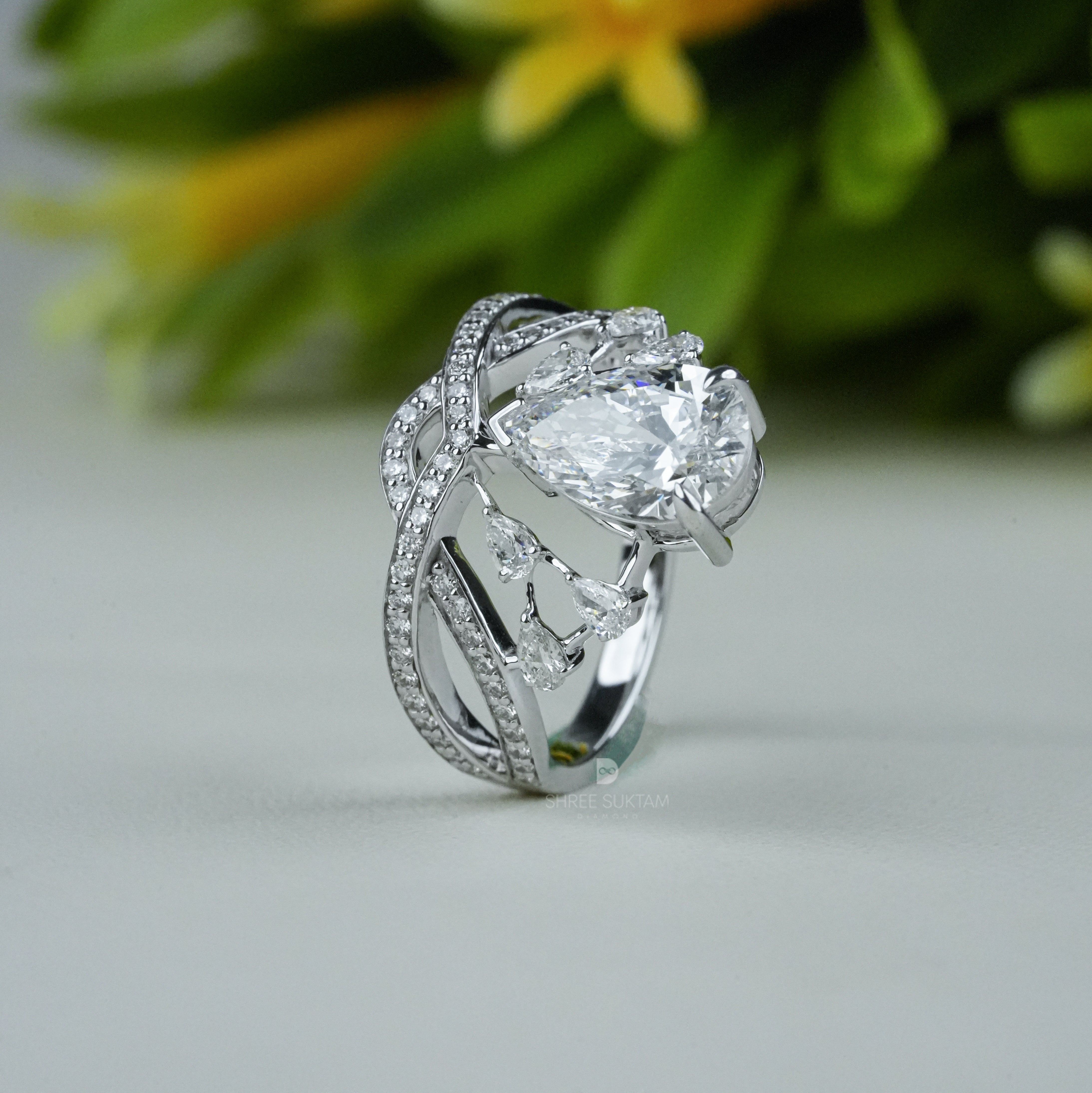 Elegant white gold tiara-inspired engagement ring featuring a stunning pear-shaped center diamond. The crown-style design is accentuated with smaller round diamonds on a double band adorned with pavé-set stones. Perfect for a bride who desires a regal and unique bridal look, this handmade piece combines royalty-inspired elegance with modern sophistication. Ideal as a proposal, promise, or anniversary ring.