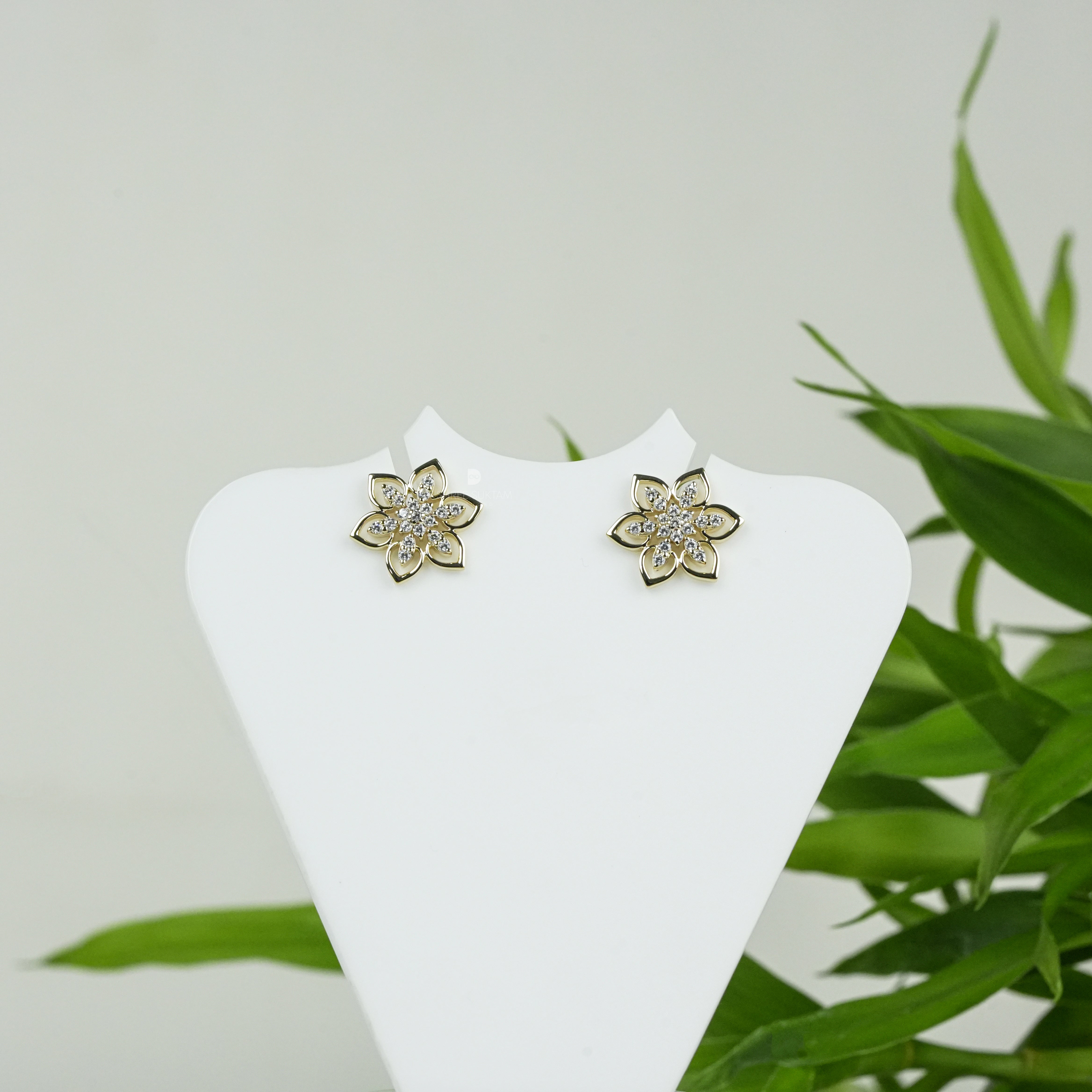 Elegant gold floral stud earrings featuring a delicate six-petal flower design adorned with sparkling cubic zirconia stones, perfect for everyday wear or special occasions. Crafted with fine attention to detail, these gold-plated earrings add a touch of timeless charm and sophistication. Ideal as a gift for women, these versatile studs pair beautifully with both casual and formal outfits, enhancing any jewelry collection.